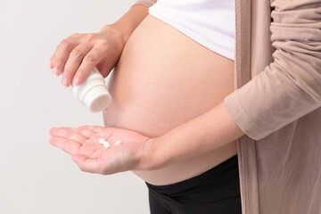 Portrait of Beautiful pregnant woman taking pill and vitamin over white background studio, health and maternity concept