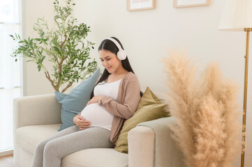 Happy pregnant woman with headphones listening to mozart music and lying on sofa, pregnancy concept