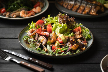 Warm veal salad with lettuce served on a dark wooden table