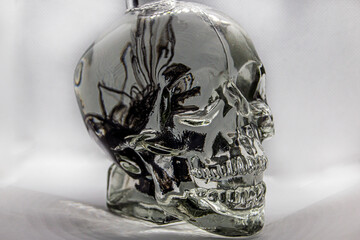 trickles, curls, figures and waves of falling ink in a transparent glass jar in the shape of a...