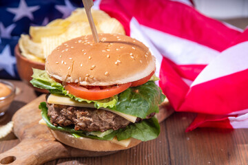 Tasty cheeseburger, chips and sauce with patriotic american flag. July 4th, Independence day picnic party food, usa themed  bbq hamburger copy space
