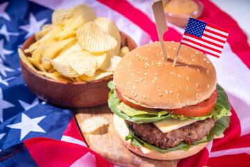 Tasty cheeseburger, chips and sauce with patriotic american flag. July 4th, Independence day picnic...