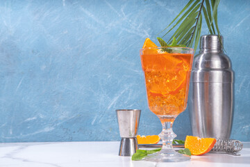 Classic italian aperitif aperol spritz cocktail in glass with ice cubes, alcohol sweet long alcohol drink with slice of orange and mint, on white background with hard light and bar utensils