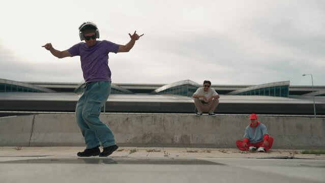 Group of asian break dancer perform street dance with multicultural friend support and moving hip hop music. Attractive handsome hipster practice b boy dance at street. Outdoor sport 2024. Sprightly.