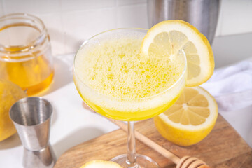 Sweet and sour boozy alcohol bee's knees cocktail. Homemade citrus honey bees knees drink with ingredients, on white background with hard light and bar utensils