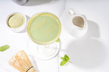 Creamy matcha martini cocktail Matchatini, trendy cold summer cocktail. Matcha non-alcohol mocktail or alcohol cocktail, in martini glasses with green matcha powder, with hard light background