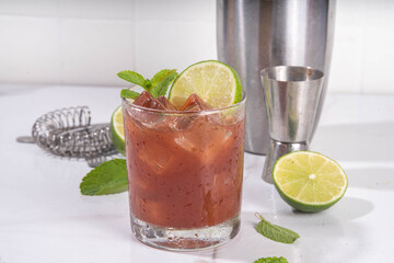 Black mole sweet margarita cocktail with black cocoa or chocolate syrup, orange juice, mezcal and soda water, trendy boozy alcohol drink, on white background with hard light and bar utensils