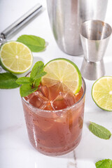 Black mole sweet margarita cocktail with black cocoa or chocolate syrup, orange juice, mezcal and soda water, trendy boozy alcohol drink, on white background with hard light and bar utensils
