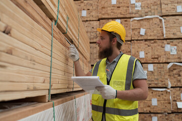 Male warehouse worker working and inspecting barcode of products in wooden warehouse storage. Male...