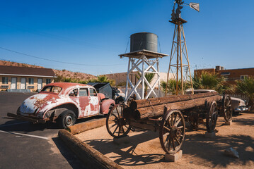 Vintage scene in Barstow, USA w or old wooden wagon, rusty Beetle car, windmill, and motel....