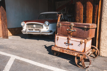 Vintage scene in Barstow, USA along Route 66. Rusted luggage cart with leather suitcases, classic...