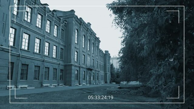 Surveillance camera no people shot of 20th century red brick three storey building facade with part of main courtyard on summer day