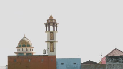 View of the mosque building with a stretch of  green rice fields with clear bright sky as background