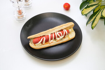 Hot dog sandwich in a black plate on a white background