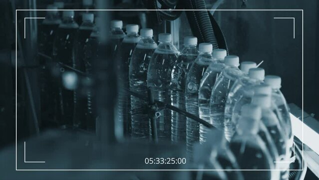 CCTV camera shot of gloved hand of anonymous factory worker putting full capped plastic bottle of soda or beer to moving conveyor belt with at beverage plant