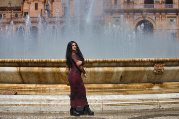Latin woman, brunette with curly hair, young and beautiful is standing next to the central fountain...