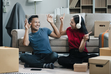 Young couple relaxing sitting on the floor around cardboard boxes at home, smiling happy moving to...