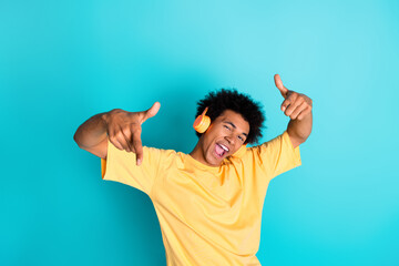 Portrait of ecstatic man with afro hairstyle wear oversize t-shirt in headphones indicating at you...