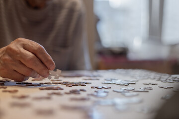 puzzle piece in a man's hand, old man putting puzzles together at home
