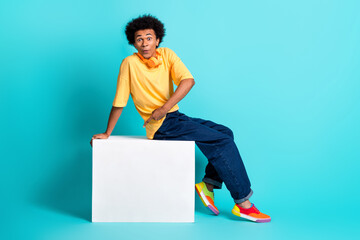 Full length photo of impressed guy dressed yellow t-shirt jeans indicating at cube empty space isolated on turquoise color background