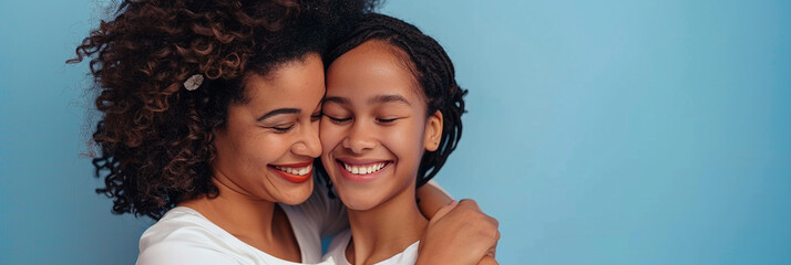 Happy mother and daughter smiling and hugging against the blue background