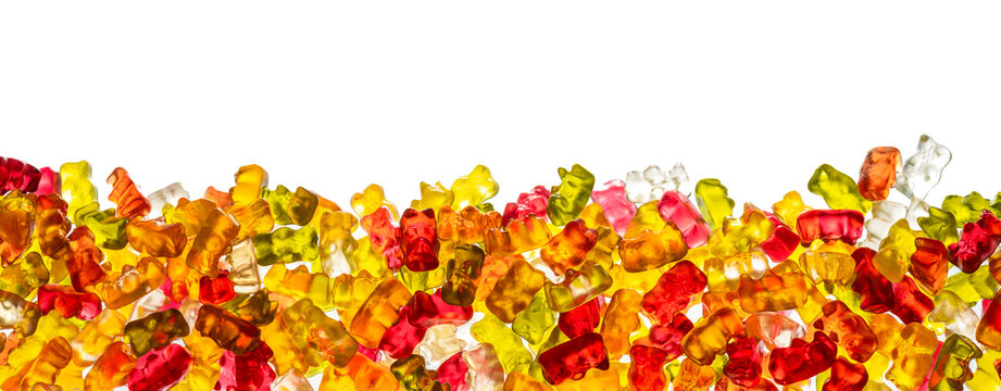 A panorama, banner, border of different colored gummy bears in front of a white background