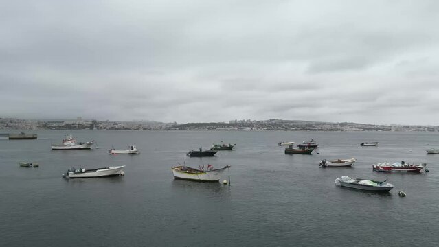 Spectacular drone footage of Trafaria Silopor Harbor captures vibrant maritime activity. Cargo ships unload against the charming coastal town backdrop. Perfect for travel and maritime projects.