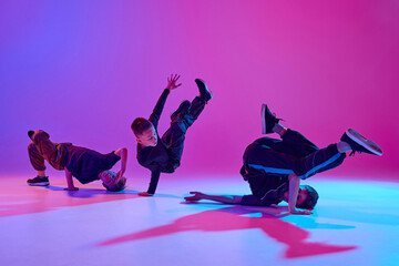 Energetic photo of talented boys, in black attire dancing hip-hop in motion in mixed neo n light...