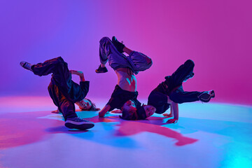 Urban dance performance. High-energy dance performance by three young boys in mixed neon light against vibrant gradient background. Concept of sport and hobby, music, fashion and art, movement. Ad © Lustre Art Group 