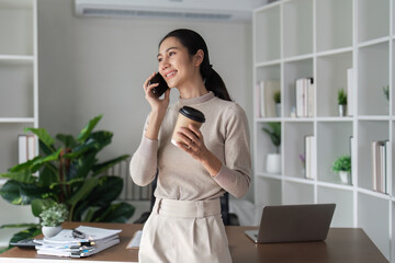 A woman is talking on her cell phone while holding a coffee cup