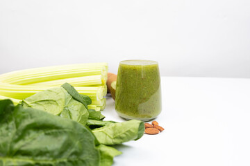 Green spinach and celery smoothie in a glass on white background, copy space for text.