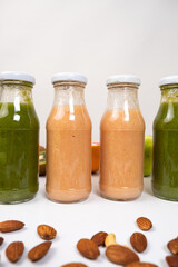 Different vegetable and fruit smoothies in glass bottles on white background.