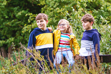 Three siblings children. Two kids boys and little girl having fun together on nature