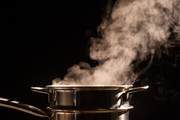 A boiling pot steams up as a chef cooking steam food in steam pot in a restaurant.	