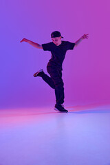 Young male dancer in motion performing an energetic street dance in mixed neon light against vibrant gradient background. Concept of sport and hobby, music, fashion and art, movement. Ad