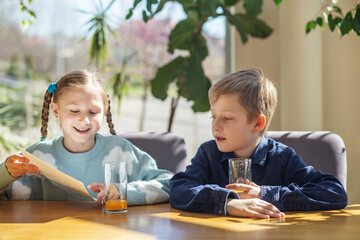 Children Reading Menu Together at Sunlit Table, Enjoying Juice
