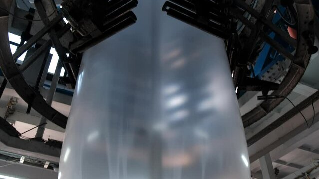 Shrink film by old technology extrusion blown film plastic bag making machine. The operation of automatic plastic bag production machine.