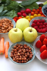 Apples, lemons, bananas, berries, carrots, leek, tomatoes, radishes, spinach and various nuts on white background. Healthy seasonal fruit and vegetable. Selective focus.