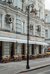 Street with tables of cafe in center of Moscow in Russia. Cozy cityscape in Moscow. Architecture and landmarks of Moscow.
