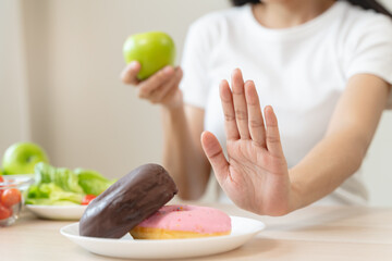 Woman on dieting for good health concept. Close up female using hand push out her favourite donut...