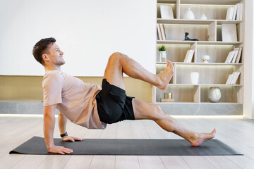 A mature man performs a yoga pose on a mat in a well-lit, modern living room, demonstrating health and vitality.