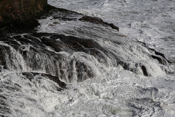White, foamy waves strike the shore of a rocky shoreline of the Pacific Ocean along the coast of northern California.