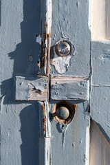 Detail of a weathered, wooden, painted door, handle and lock.