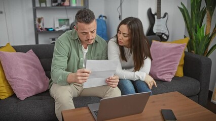 A couple reviews documents together in the living room, portraying themes of partnership, domestic life, and decision-making.