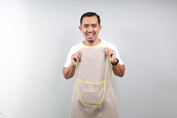 Confident barista in brown apron standing against white background. Waiter smiling and looking happy