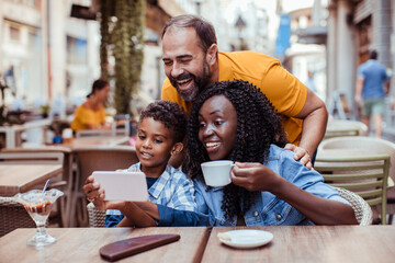 Happy multiracial family taking a selfie at an outdoor cafe