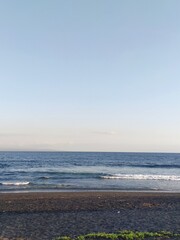 ocean wave on the island of Bali crashes onto the rocky shore, a clear sunny day, blue sky