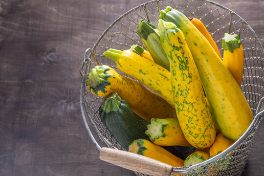 Yellow green leopard spotted zucchini. Vegetables on the table. vegetable marrow harvest. Food background. Fresh courgette, cropped summer squash. Picked courgettes. Still life in kitchen.