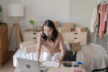 Busy Asian woman preparing package delivery box Shipping for shopping online taking note of order...