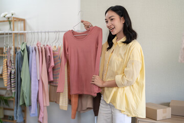 Young Asian girl Online consultation with stylist designer take online video course or training of stylish clothes on hangers clothing Asian Woman dressmaker working in fashion studio